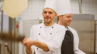 Ein Koch wirft einen Pfannkuchen in die Luft