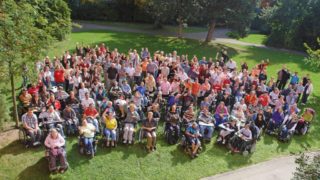 Viele Menschen stehen auf einer Wiese und winken