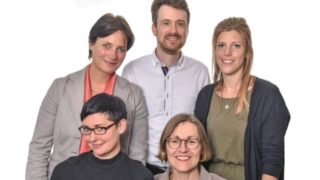 Ein Mann und vier Frauen stehen als Team zusammen