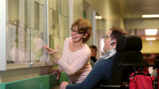 Zwei Personen stehen am Schaukasten und schauen auf die Neuigkeiten