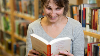 Eine junge Frau liest ein Buch in der Bibliothek