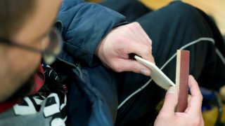Eine Person schleift ein Stück Holz ab