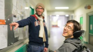 Eine Person zeigt einer anderen etwas im Schaukasten