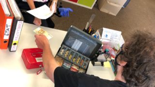 Ein Mann zahlt einer Mitarbeiterin Geld für Ihre Fahrkarte aus