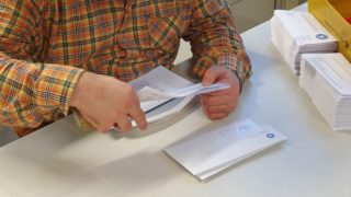 Eine Person kuvertiert Briefe ein