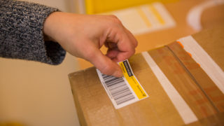 Eine Person klebt einen Post-Aufkleber auf ein Paket