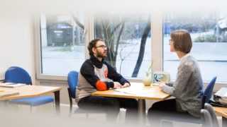 Zwei Personen sitzen sich gegenüber und führen ein Gespräch