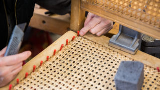 Eine Person arbeitet an der Sitzfläche eines Stuhls