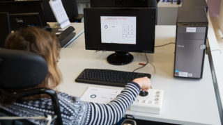 Eine junge Frau am Computer beidient eine Joystick-Maus