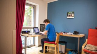 Mann sitzt vor einem Laptop am Schreibtisch