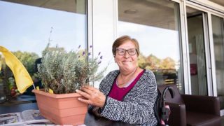 Frau topft auf dem Balkon Blumen ein