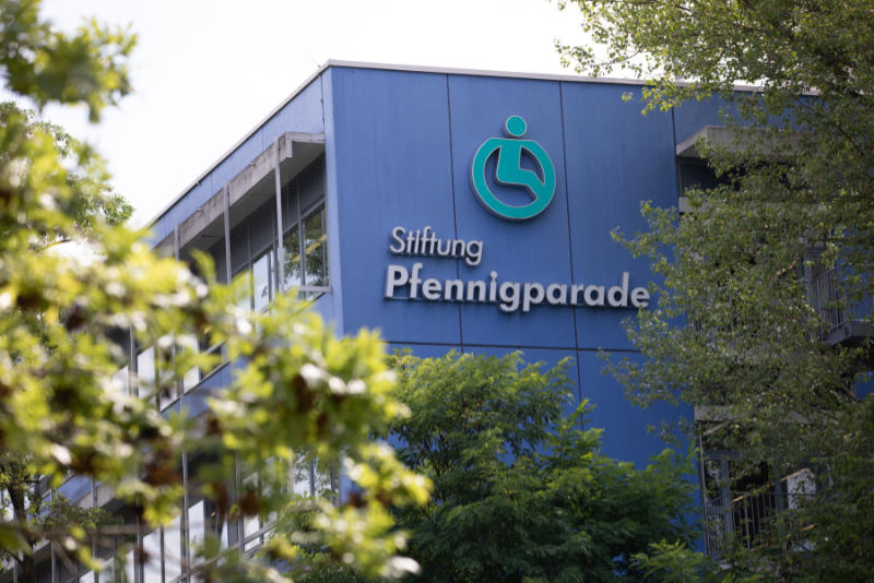 Logo Stiftung Pfennigparade am Stammsitz, umrahmt von Bäumen