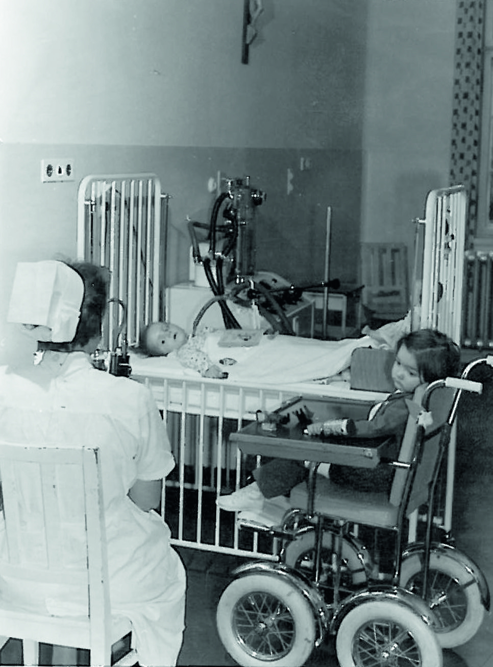 Eine Krankenschwester sitzt bei zwei Patienten im Krankenzimmer
