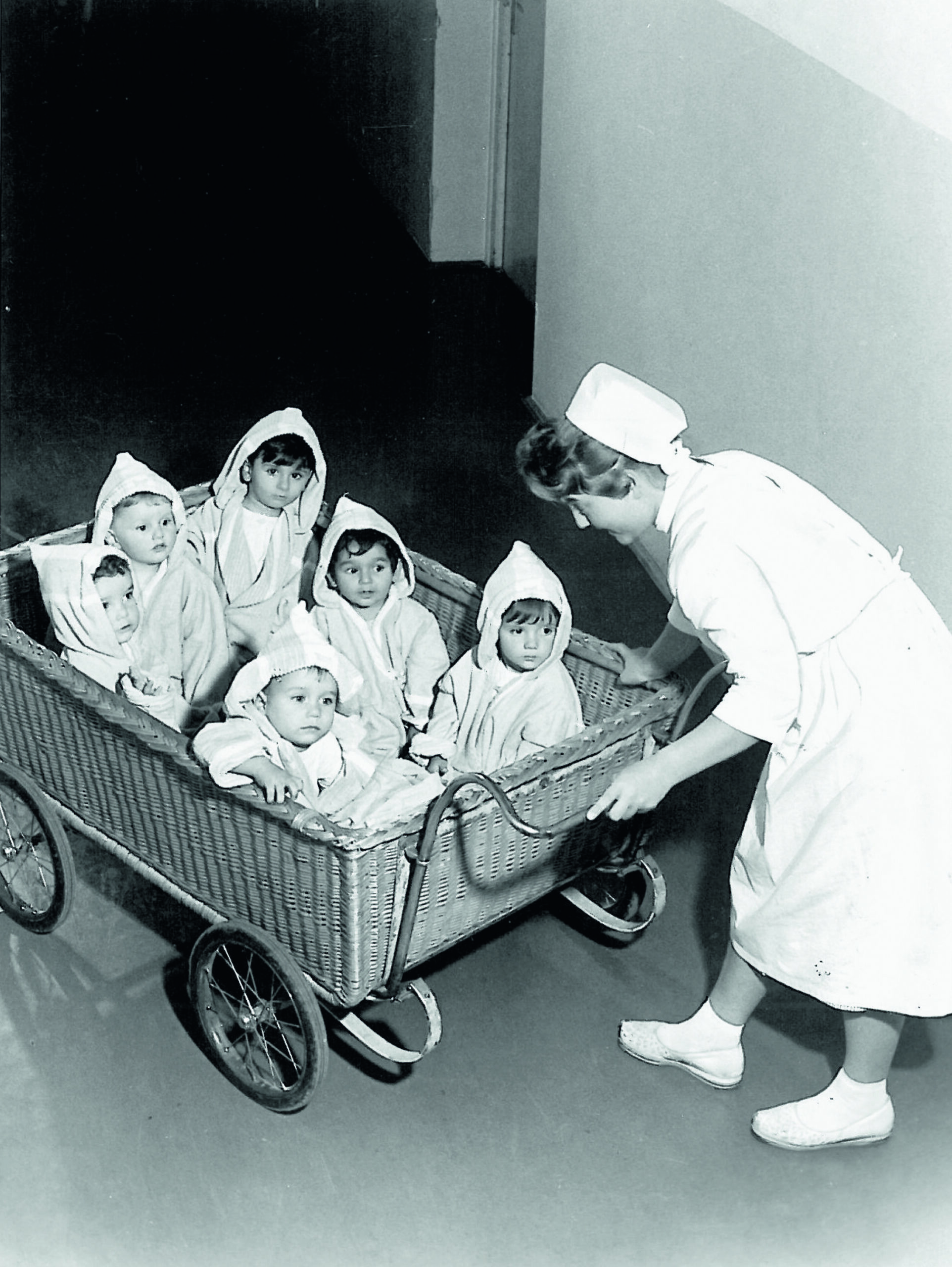 Mehrere Kinder werden von einer Krankenschwester in einen Wagen gezogen