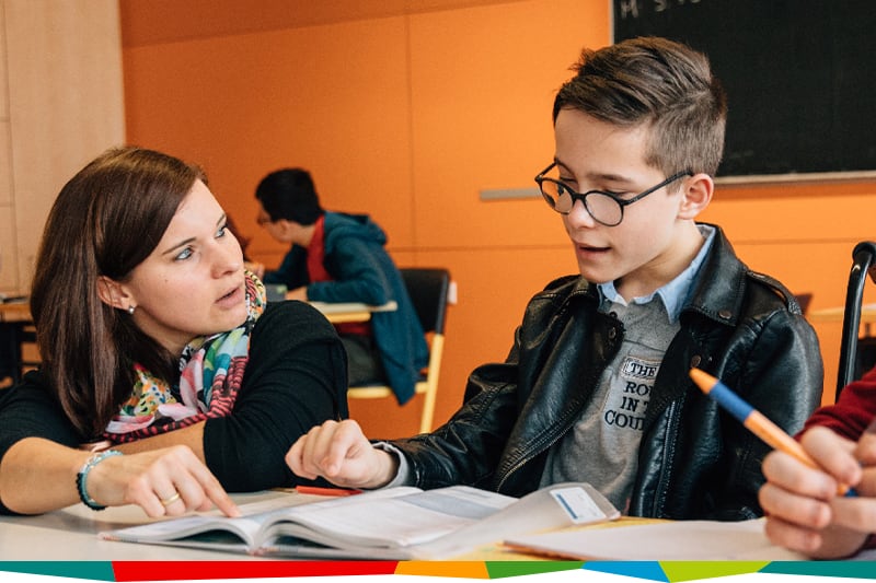 Zwei Personen sitzen an einem Tisch vor einem aufgeschlagenen Buch
