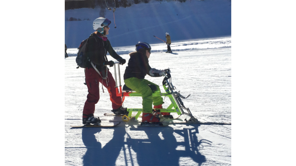 Person mit Begleiter beim Skibobfahren im Schnee