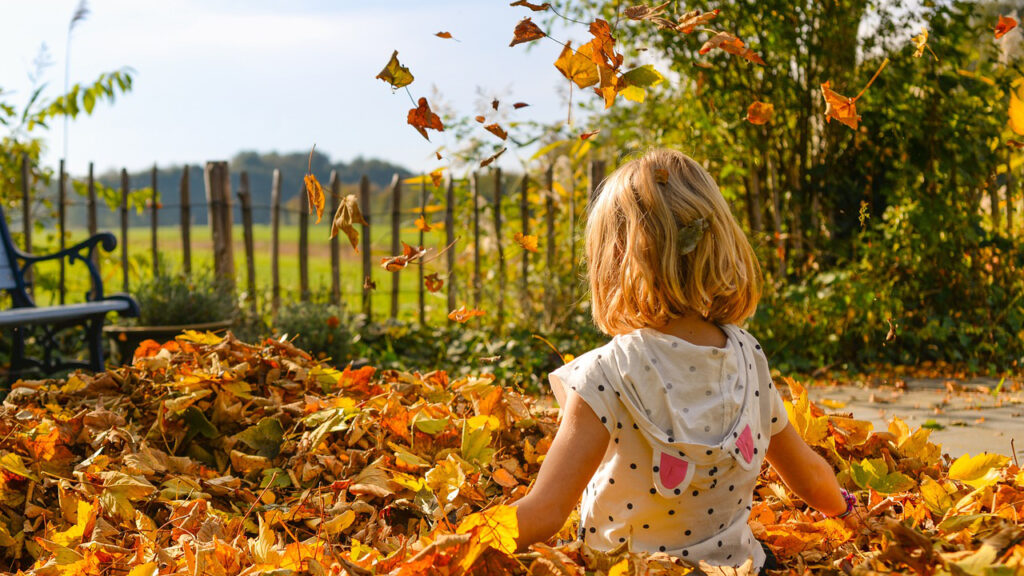 Mädchen steht im Herbstlaub