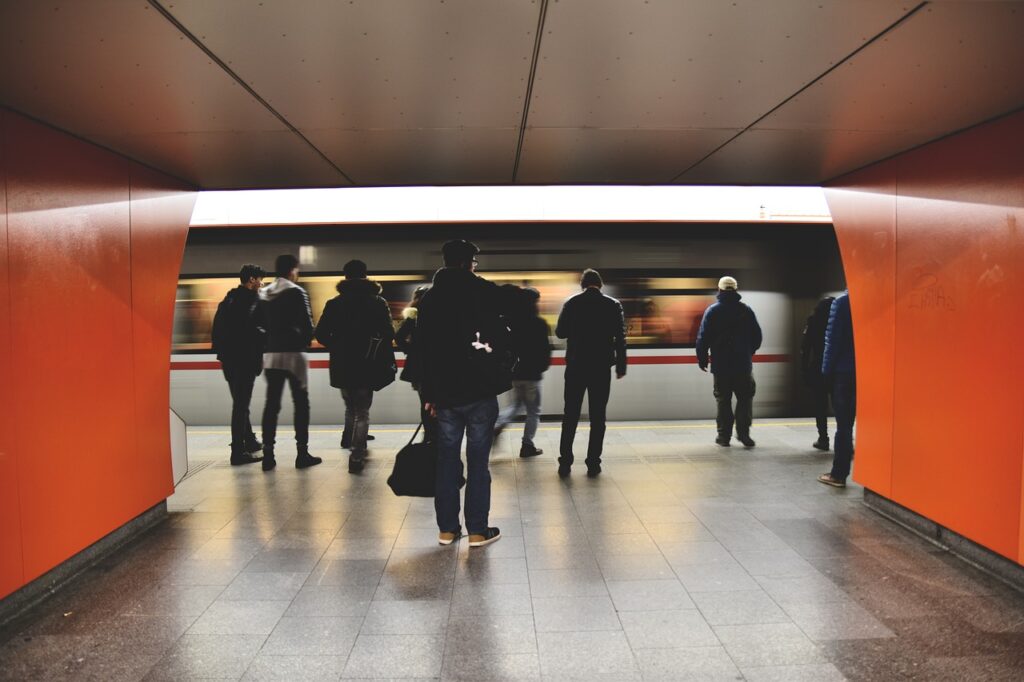 Viele Menschen am Bahnsteig vor einfahrendem Zug