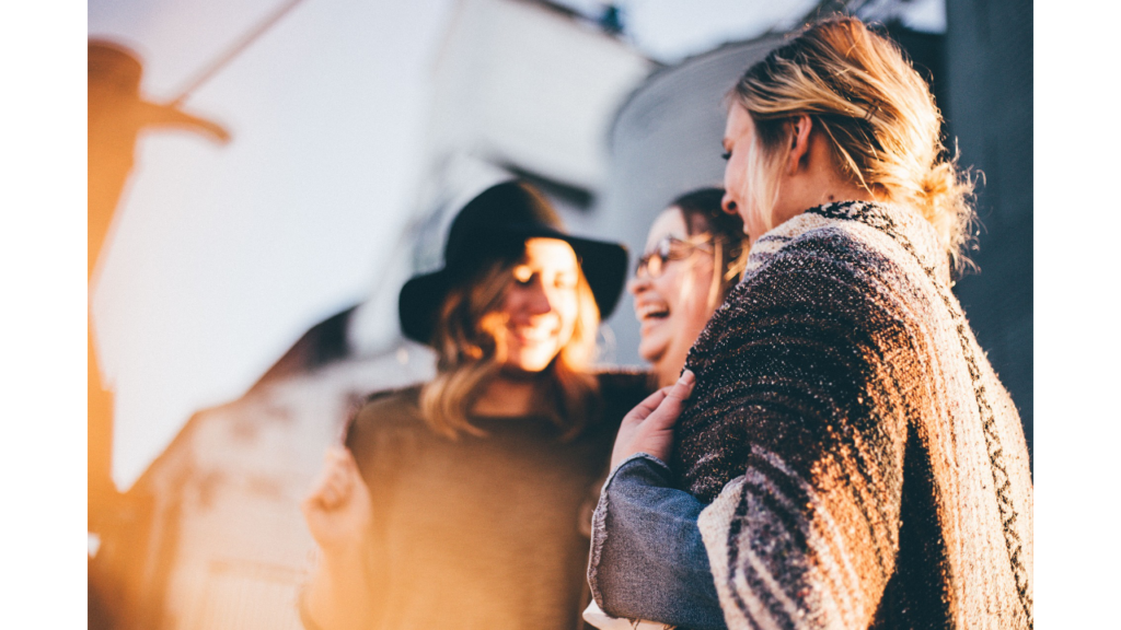  Draußen stehen drei Frauen nebeneinander und lachen