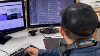 Mann programmiert an Computer mit zwei Bildschirmen