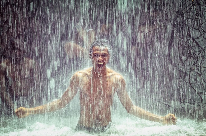 Der Man steht im Wasserfall und schreit.