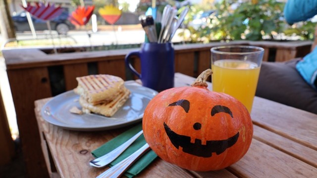 Kürbis steht mit Getränk, Panini und Besteck auf einem Tisch