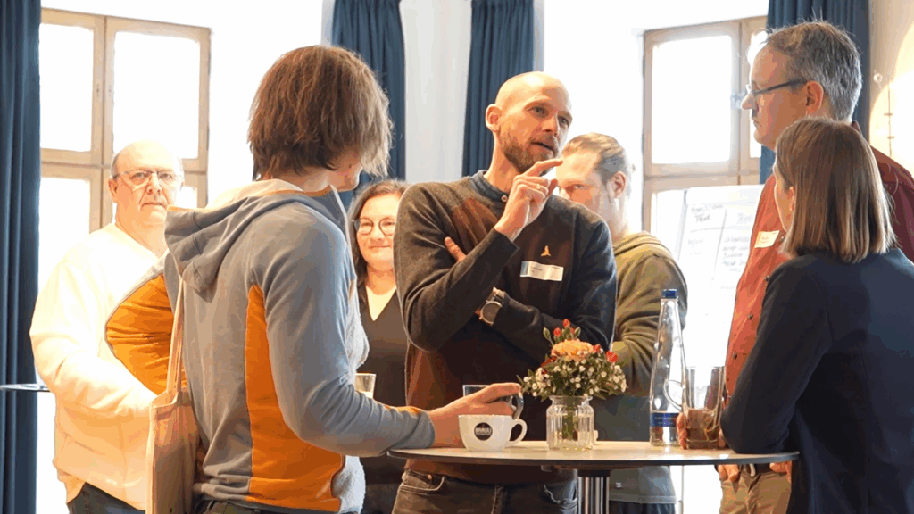 Mehrere Personen stehen um einen Bistrotisch herum