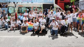 Mehrere Personen mit und ohne Rollstuhl vor CSD-Bus der Pfennigparade