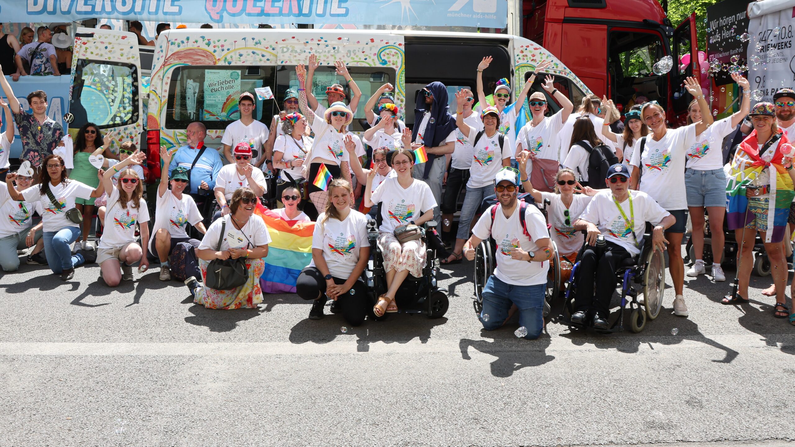 Mehrere Personen mit und ohne Rollstuhl vor CSD-Bus der Pfennigparade