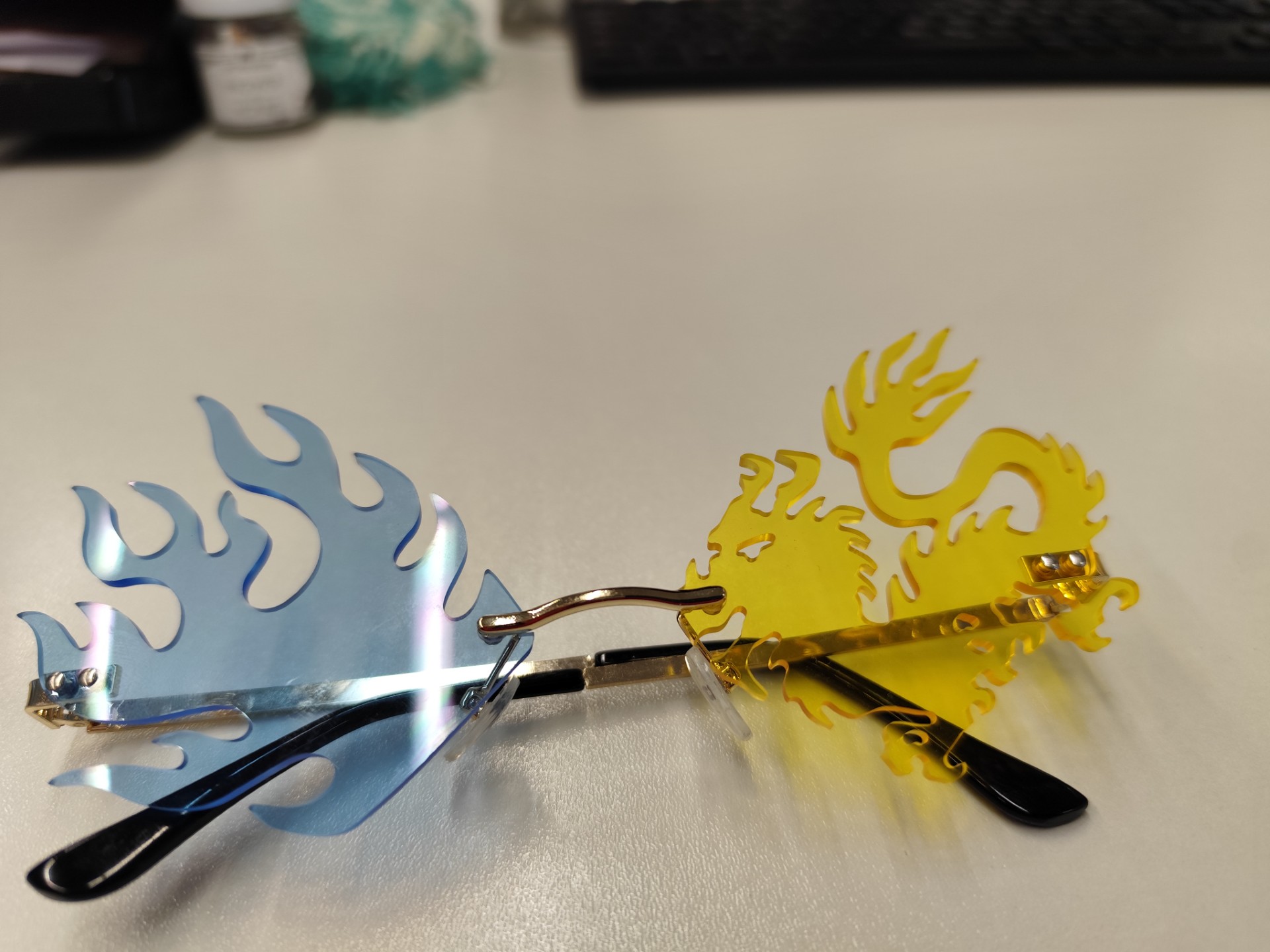 Gelbes Brillenglas in Drachenform; Ein Blaues in Fischform und goldfarbenes Gestell